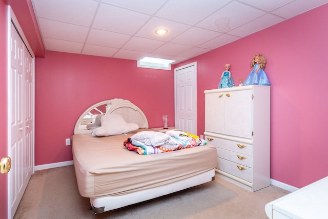 bedroom featuring a paneled ceiling, light colored carpet, and a closet