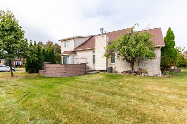 rear view of property with a lawn and central air condition unit