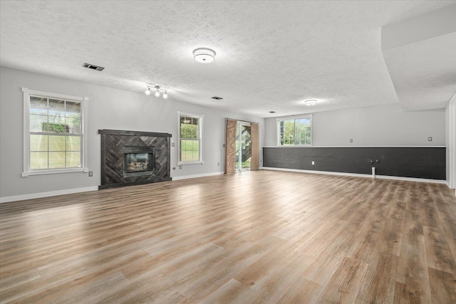 unfurnished living room with light hardwood / wood-style floors, plenty of natural light, and a premium fireplace