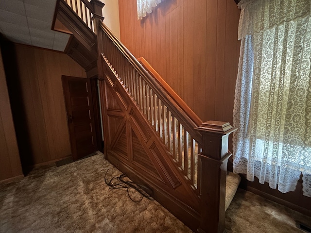 staircase featuring carpet and wooden walls