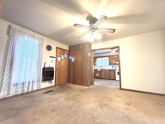 unfurnished living room featuring heating unit, light carpet, and crown molding