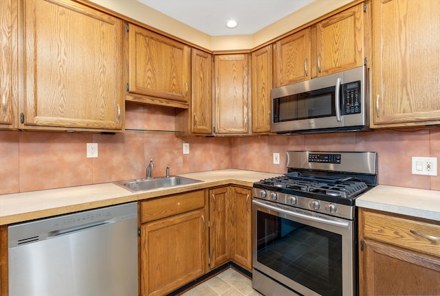 kitchen featuring appliances with stainless steel finishes, light tile patterned flooring, decorative backsplash, and sink