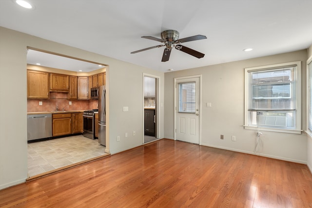 kitchen with stainless steel appliances, sink, ceiling fan, tasteful backsplash, and light hardwood / wood-style floors