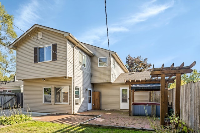 rear view of property with a pergola, a hot tub, and a patio area