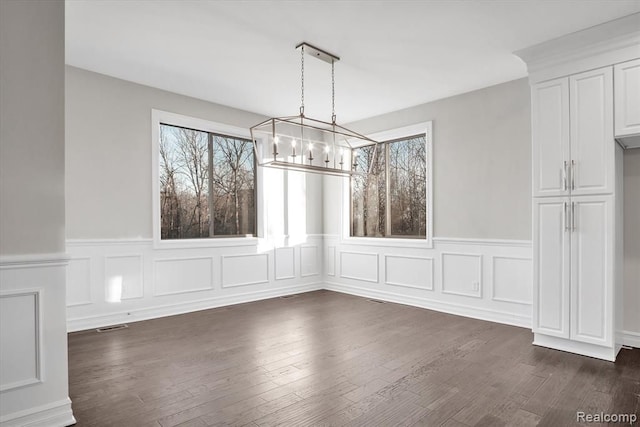 unfurnished dining area featuring dark wood-type flooring and a notable chandelier