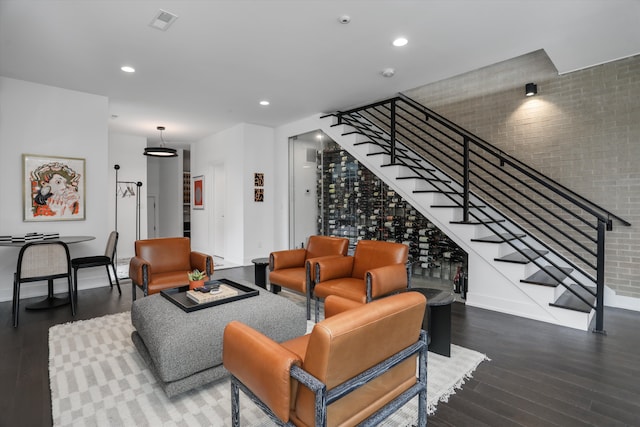 living room featuring dark hardwood / wood-style flooring and brick wall