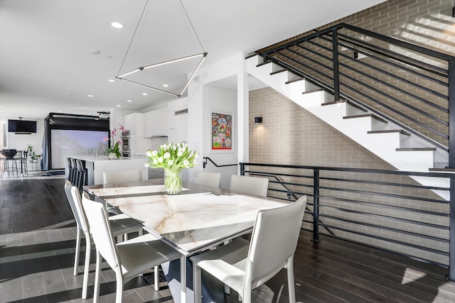 dining area with dark hardwood / wood-style floors and brick wall