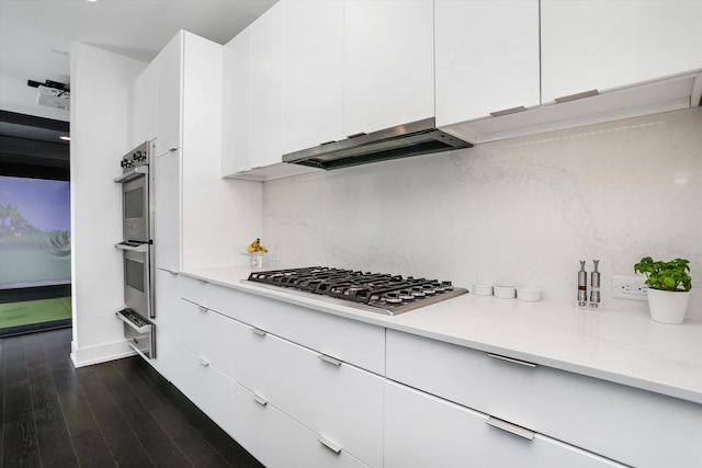 kitchen with ventilation hood, dark hardwood / wood-style flooring, white cabinets, and appliances with stainless steel finishes