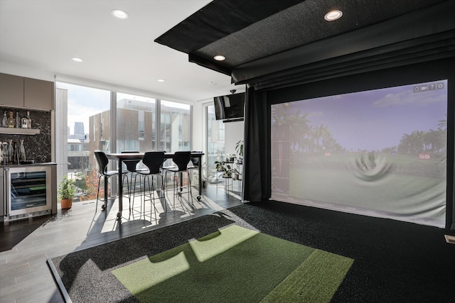 interior space featuring indoor bar, hardwood / wood-style flooring, golf simulator, and beverage cooler