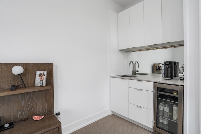 bar featuring white cabinetry, sink, beverage cooler, and light carpet