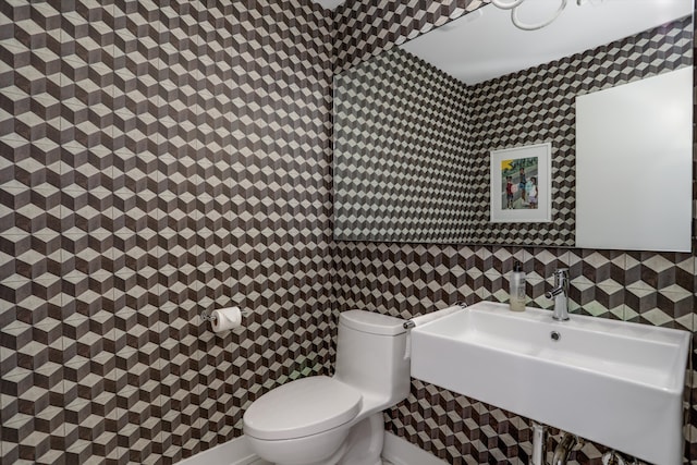 bathroom with toilet, tile walls, and sink