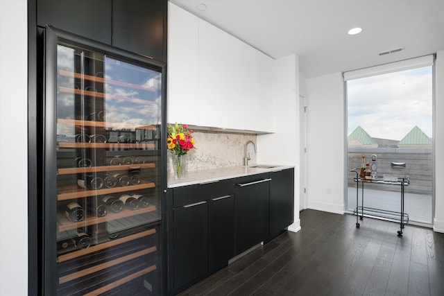 bar featuring white cabinets, dark hardwood / wood-style flooring, backsplash, and beverage cooler