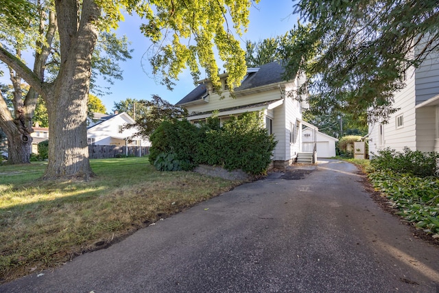 view of side of property featuring a lawn, a garage, and an outbuilding