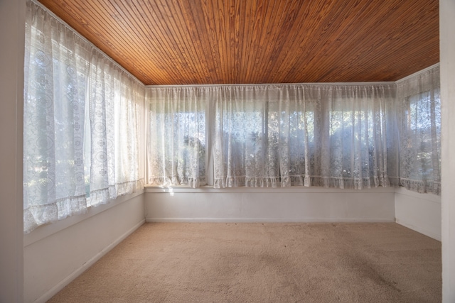 carpeted empty room with a wealth of natural light and wood ceiling