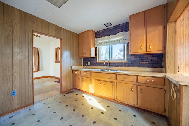 kitchen featuring tasteful backsplash, wood walls, and sink