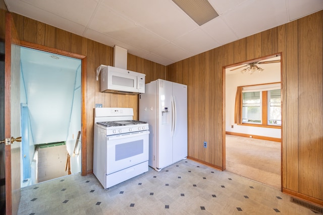 kitchen with wood walls, ceiling fan, light carpet, and white appliances