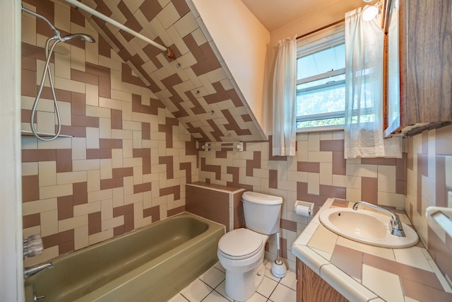 full bathroom with vanity, tile patterned floors, tiled shower / bath combo, toilet, and tile walls