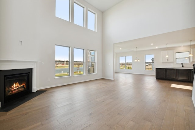 unfurnished living room with recessed lighting, a fireplace with flush hearth, wood finished floors, and baseboards