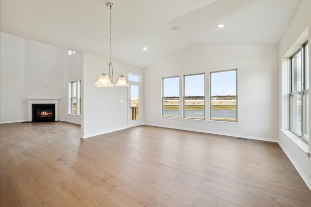 unfurnished living room with baseboards, lofted ceiling, a lit fireplace, recessed lighting, and wood finished floors