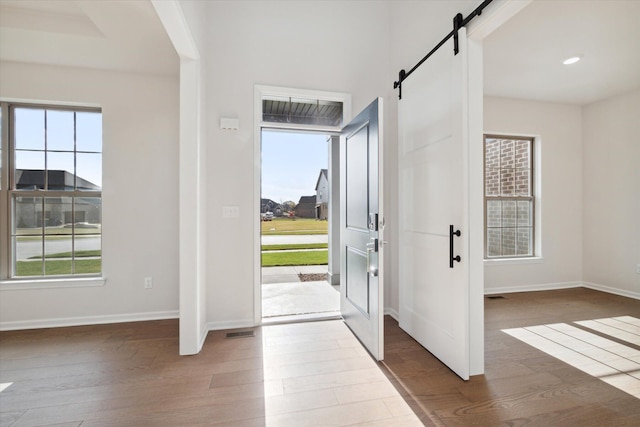 foyer with a barn door, wood finished floors, and a healthy amount of sunlight