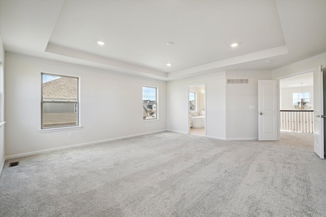 spare room with a tray ceiling and visible vents