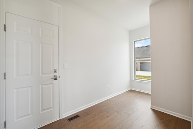 spare room with a wealth of natural light, visible vents, baseboards, and wood finished floors