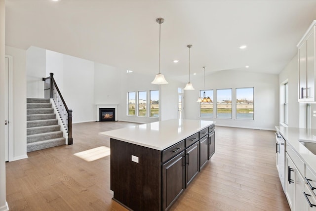 kitchen featuring open floor plan, white cabinets, light countertops, lofted ceiling, and dark brown cabinets