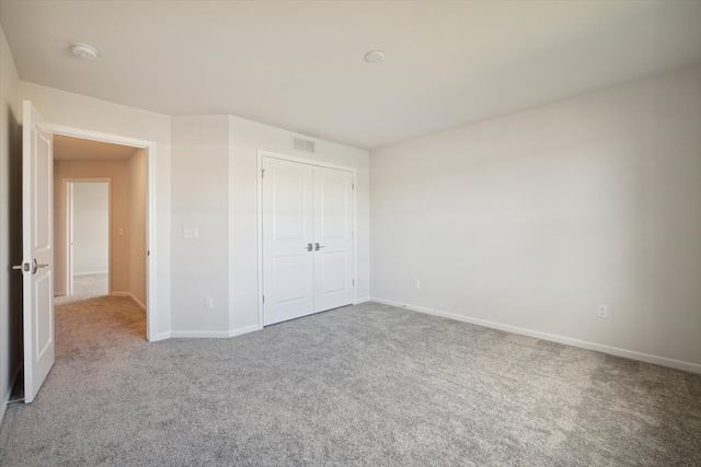 unfurnished bedroom with a closet, visible vents, baseboards, and carpet floors