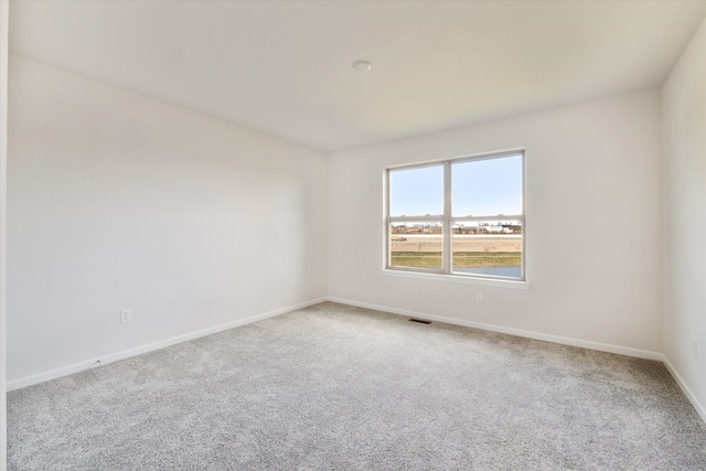 unfurnished room featuring carpet, visible vents, and baseboards