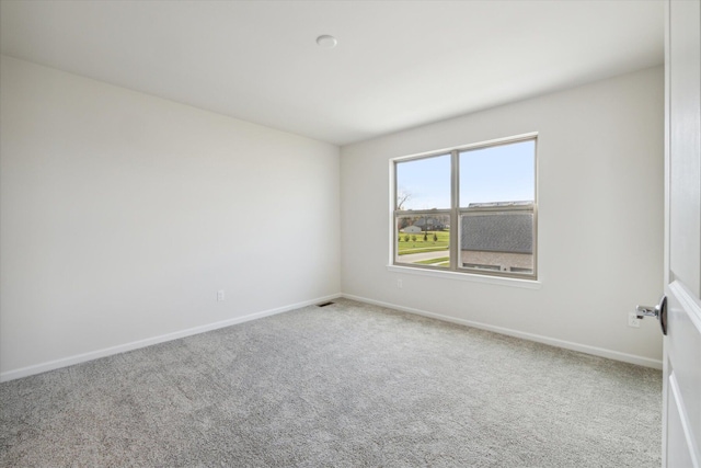 carpeted spare room featuring visible vents and baseboards