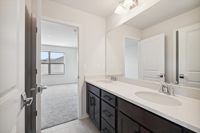 full bath featuring double vanity, tile patterned floors, baseboards, and a sink