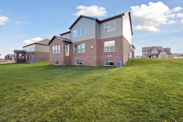 rear view of house with a yard, central AC unit, and brick siding