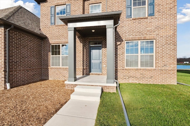 entrance to property with a yard and brick siding