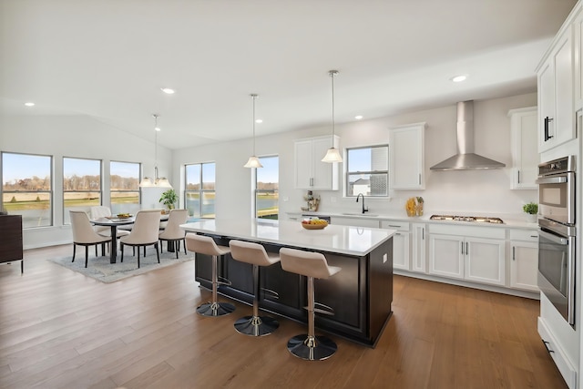 kitchen featuring a wealth of natural light, appliances with stainless steel finishes, light countertops, and wall chimney range hood
