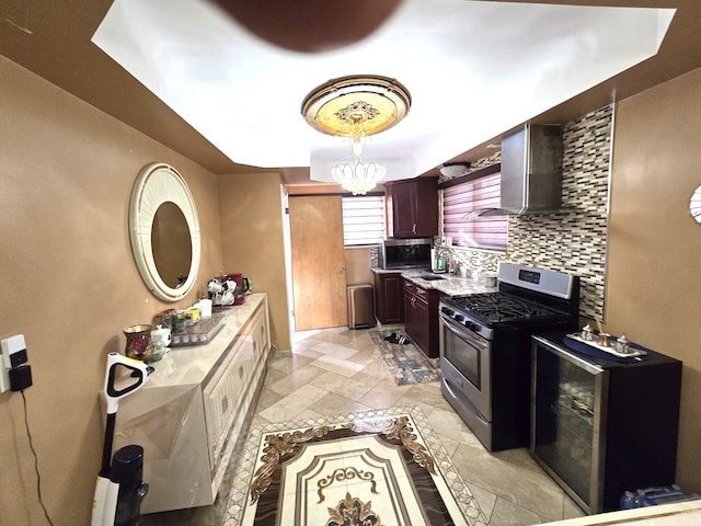 kitchen featuring decorative backsplash, an inviting chandelier, wall chimney range hood, and appliances with stainless steel finishes