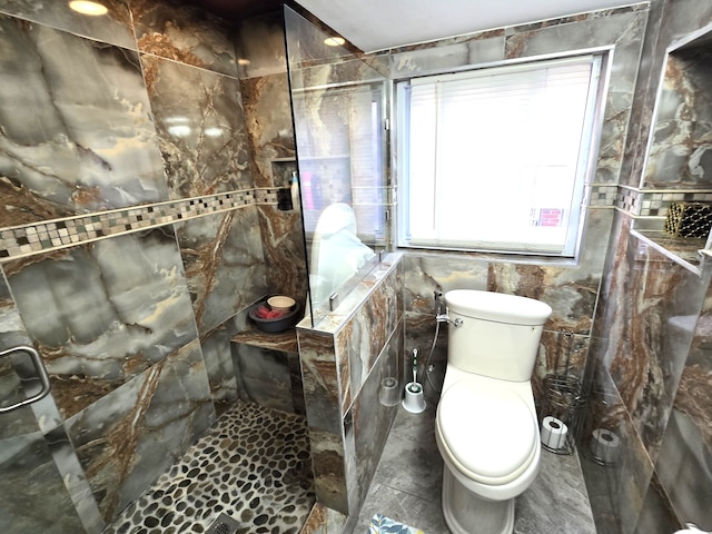 bathroom with tiled shower, toilet, and tile walls