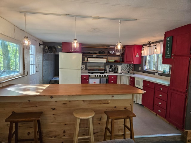 kitchen with stainless steel range, white refrigerator, wood counters, and a wealth of natural light