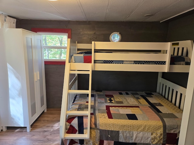 bedroom with hardwood / wood-style floors and wooden walls