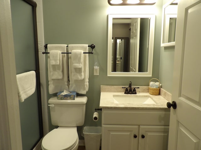 bathroom with vanity, a shower with shower door, and toilet