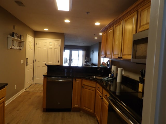 kitchen with kitchen peninsula, sink, light wood-type flooring, and stainless steel appliances