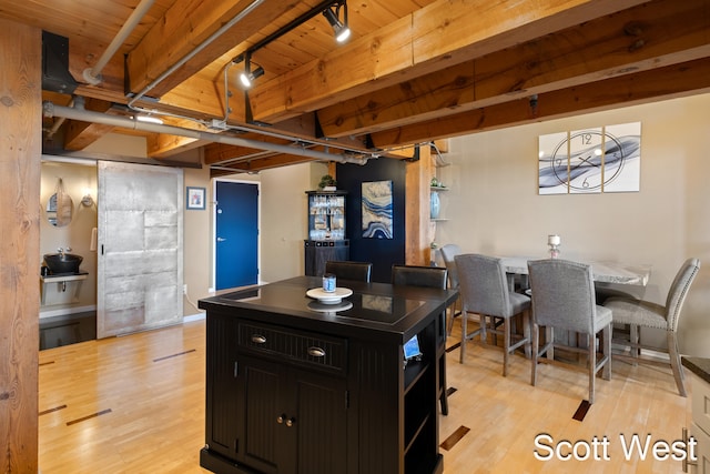 kitchen featuring beam ceiling, light hardwood / wood-style flooring, a center island, and wooden ceiling