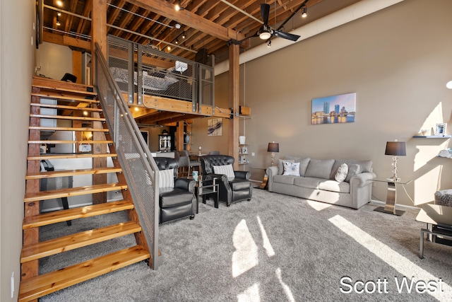 living room featuring carpet flooring, ceiling fan, beamed ceiling, and a high ceiling