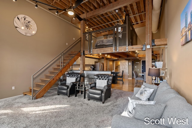 living room featuring ceiling fan, beamed ceiling, and a high ceiling