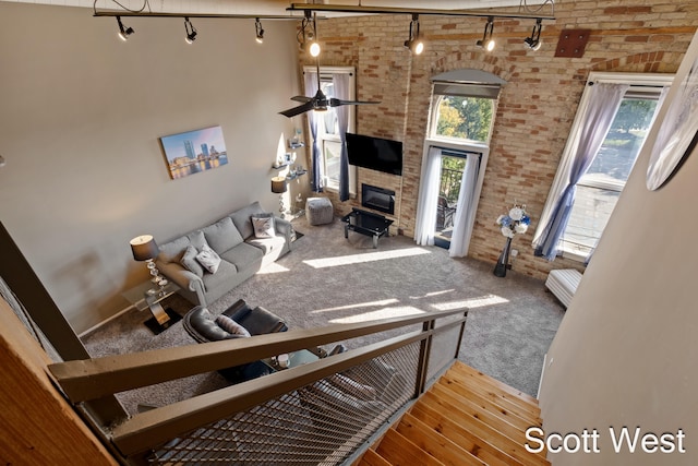 living room featuring ceiling fan, brick wall, wood-type flooring, and a high ceiling