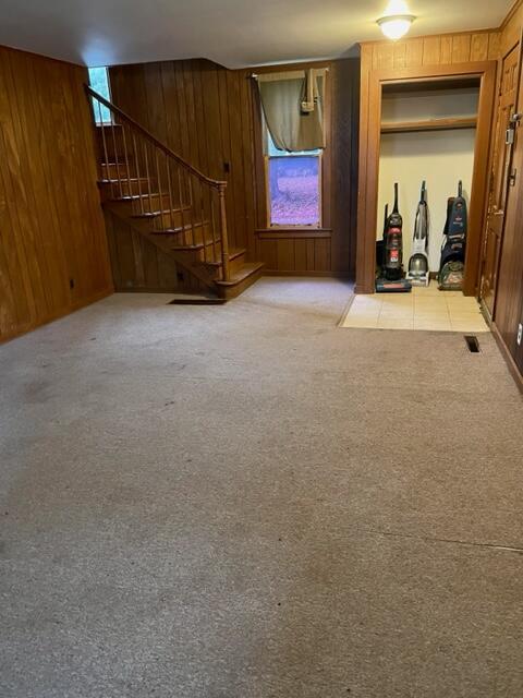 120 Oak St, Hillsdale, MI 49242 - unfurnished living room with wooden walls, stairs, and carpet