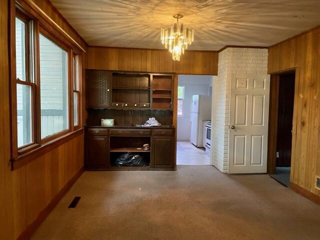 120 Oak St, Hillsdale, MI 49242 - bar area with wooden walls, a chandelier, freestanding refrigerator, decorative light fixtures, and light colored carpet