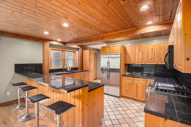 kitchen with kitchen peninsula, a kitchen bar, stainless steel appliances, and sink