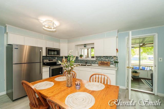 kitchen with white cabinets, sink, light hardwood / wood-style flooring, decorative backsplash, and appliances with stainless steel finishes