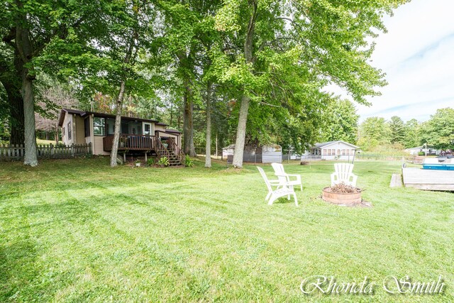 11432 Lakeshore Dr, Lakeview, MI 48850 - view of yard with a wooden deck, an outdoor fire pit, stairway, and view of wooded area