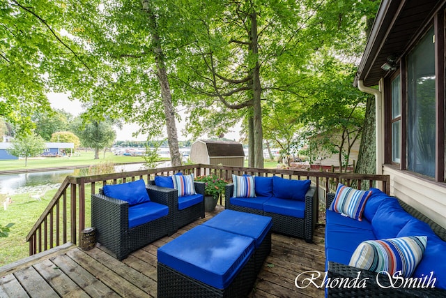 wooden deck featuring outdoor lounge area, a storage unit, and a water view